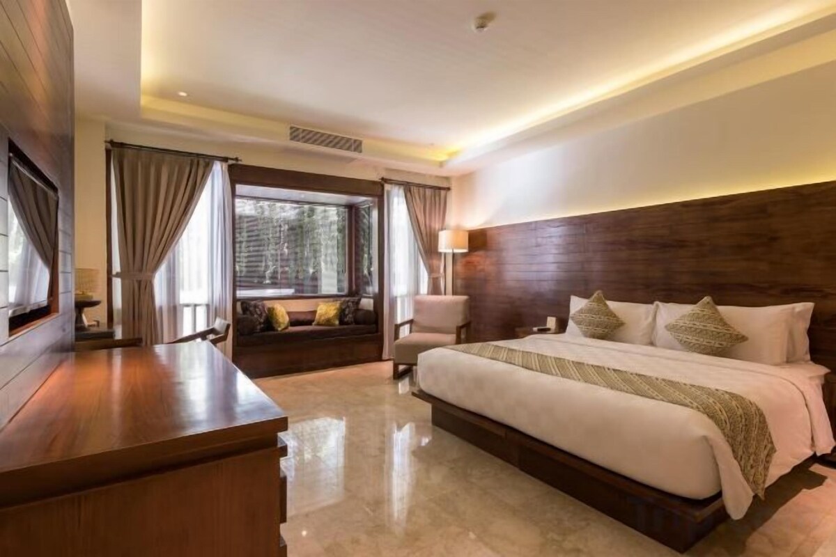 A hotel room with a large bed, a desk, and a view of the outdoors.