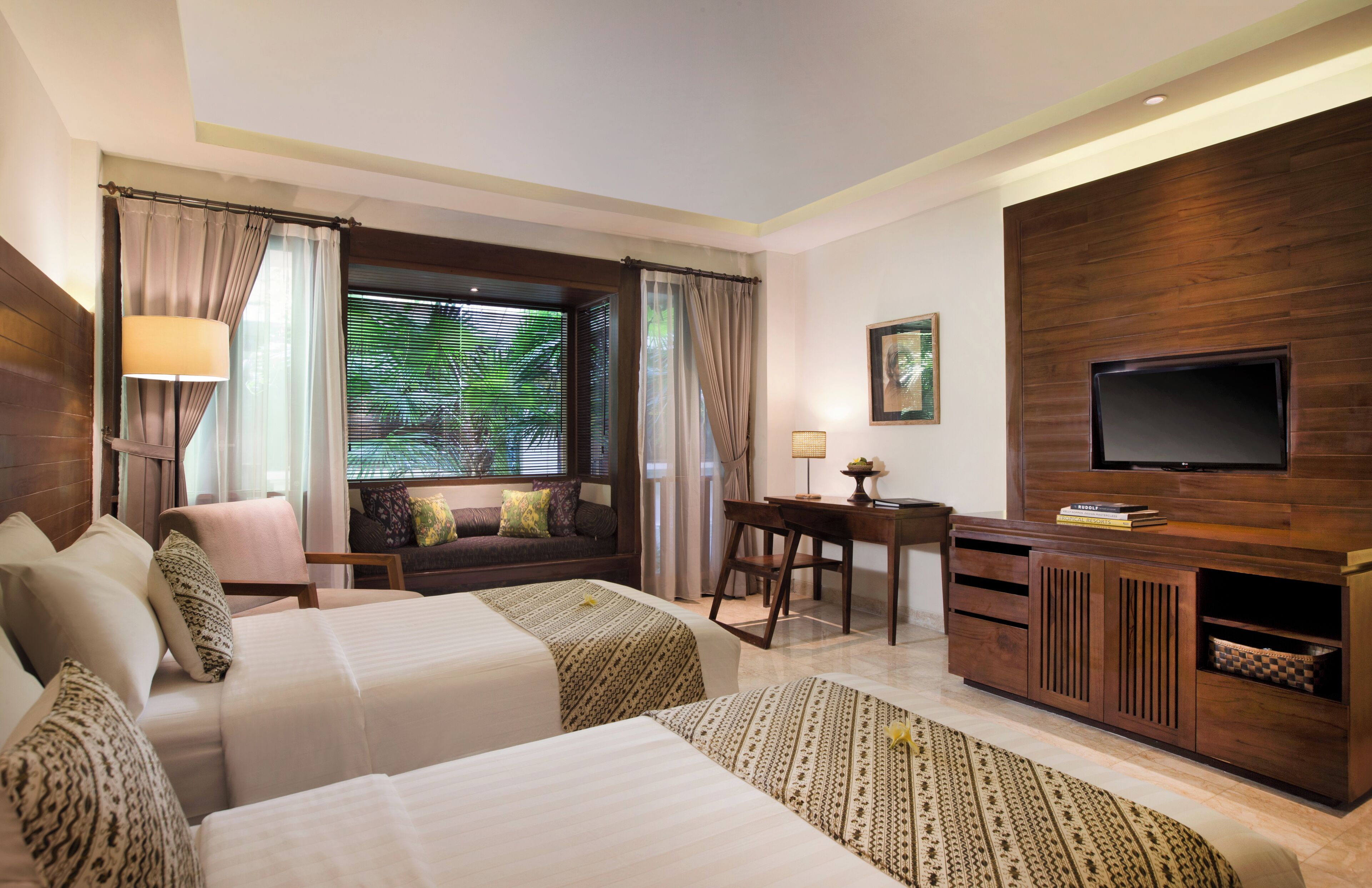 Habitación de hotel con dos camas, un escritorio, un televisor y una ventana con cortinas.