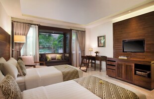 A hotel room with two beds, a desk, a television, and a window with curtains.