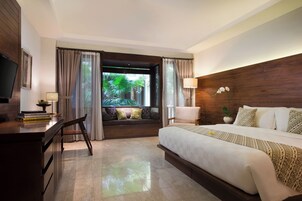 Habitación de hotel con cama, escritorio, silla, televisión y vistas a zonas verdes.