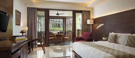 Habitación de hotel con una cama grande, un escritorio con lámpara, televisor y vistas al exterior.