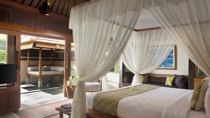 Een slaapkamer met een hemelbed, een televisie en uitzicht op de omgeving.