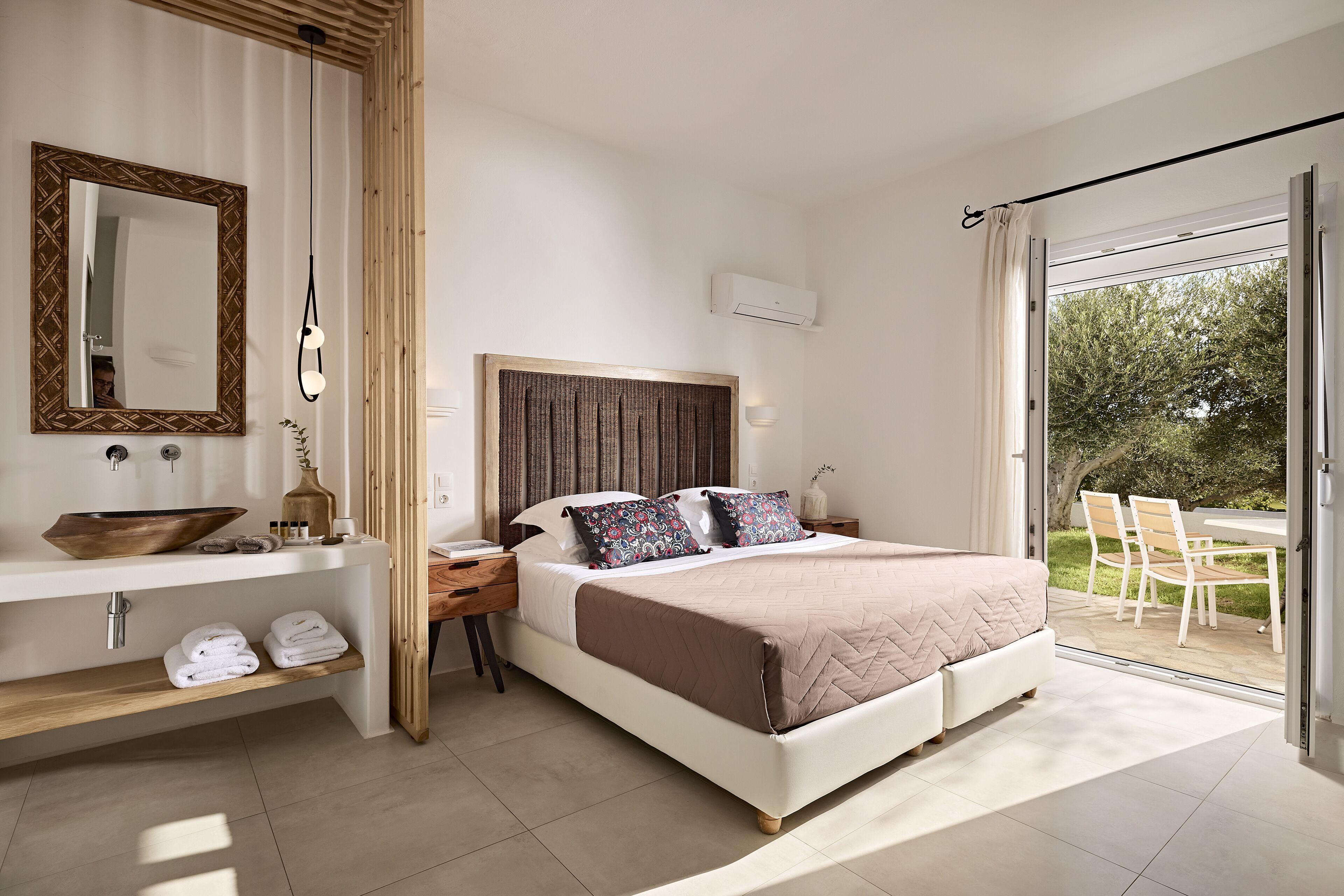 Une chambre à coucher avec un lit, des tables de chevet, un miroir, une fenêtre et une vue sur l’extérieur.