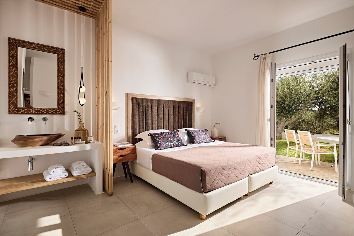 A bedroom with a bed, bedside tables, a mirror, a window, and a view of the outdoors.