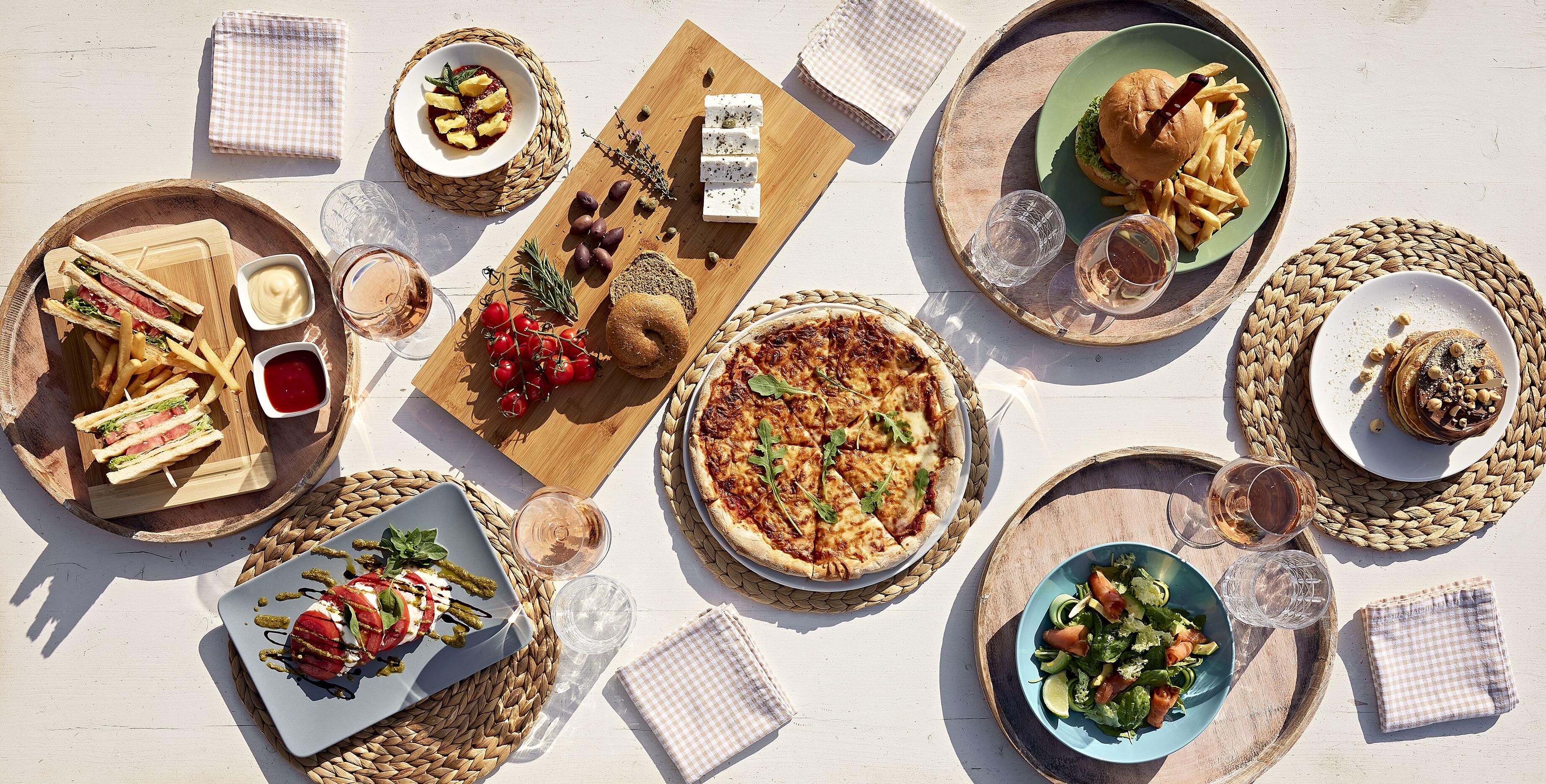 A table set with various dishes including sandwiches, pizza, salad, and drinks, suggesting a meal setup.