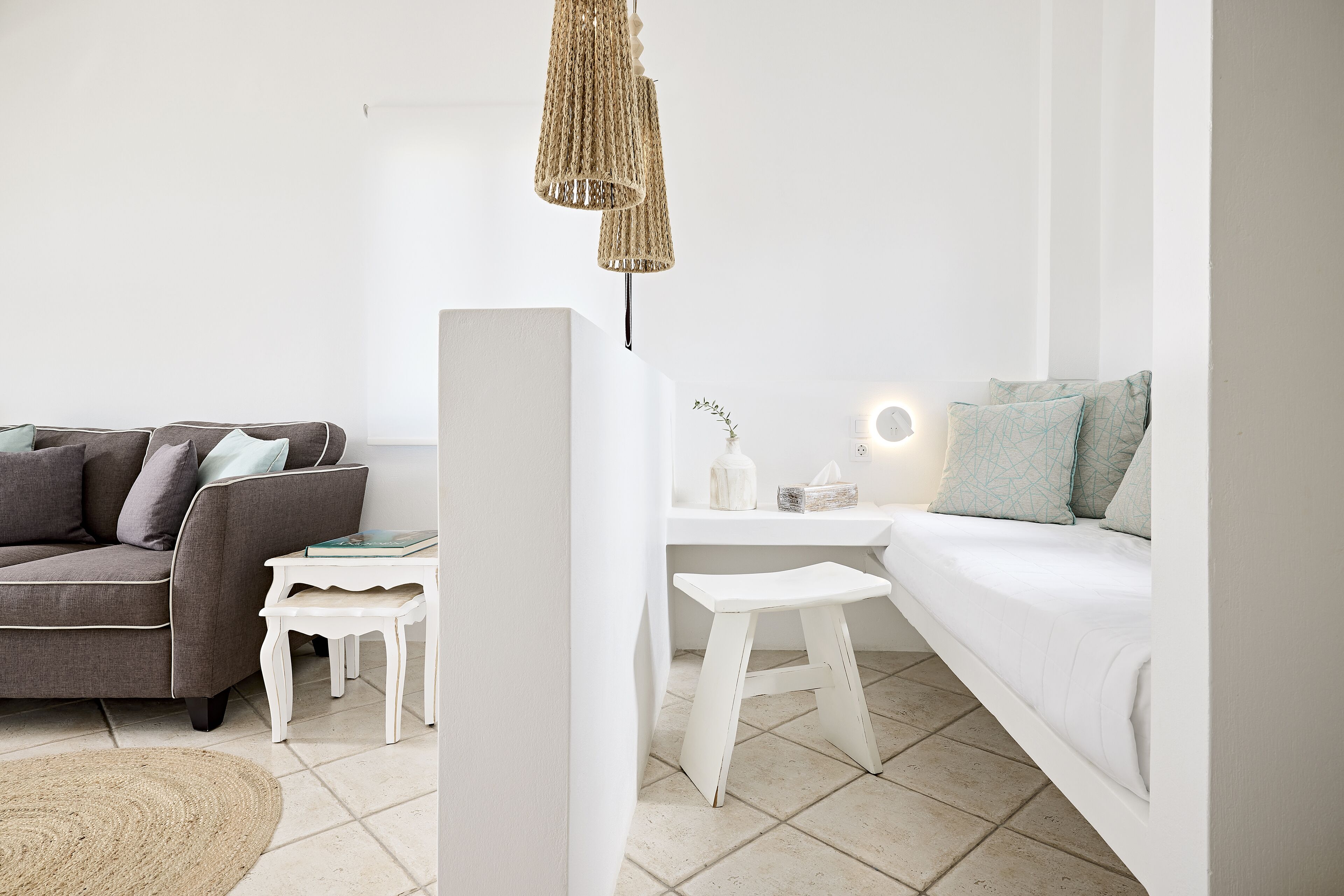 En moderne stue med en grå sofa, et hvidt sofabord og en sofa i hvid med mønstrede puder.