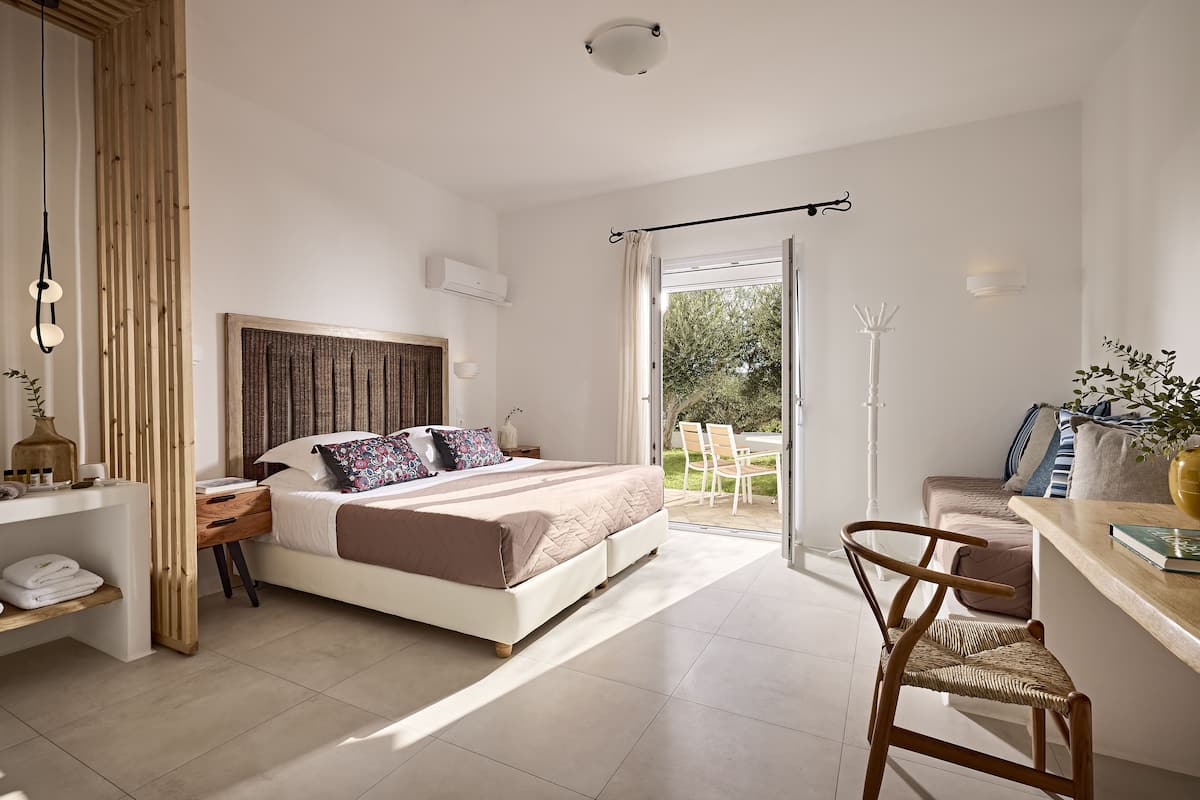 Ein modernes Schlafzimmer mit einem großen Bett, Nachttischen, einem Sessel und Blick ins Freie.