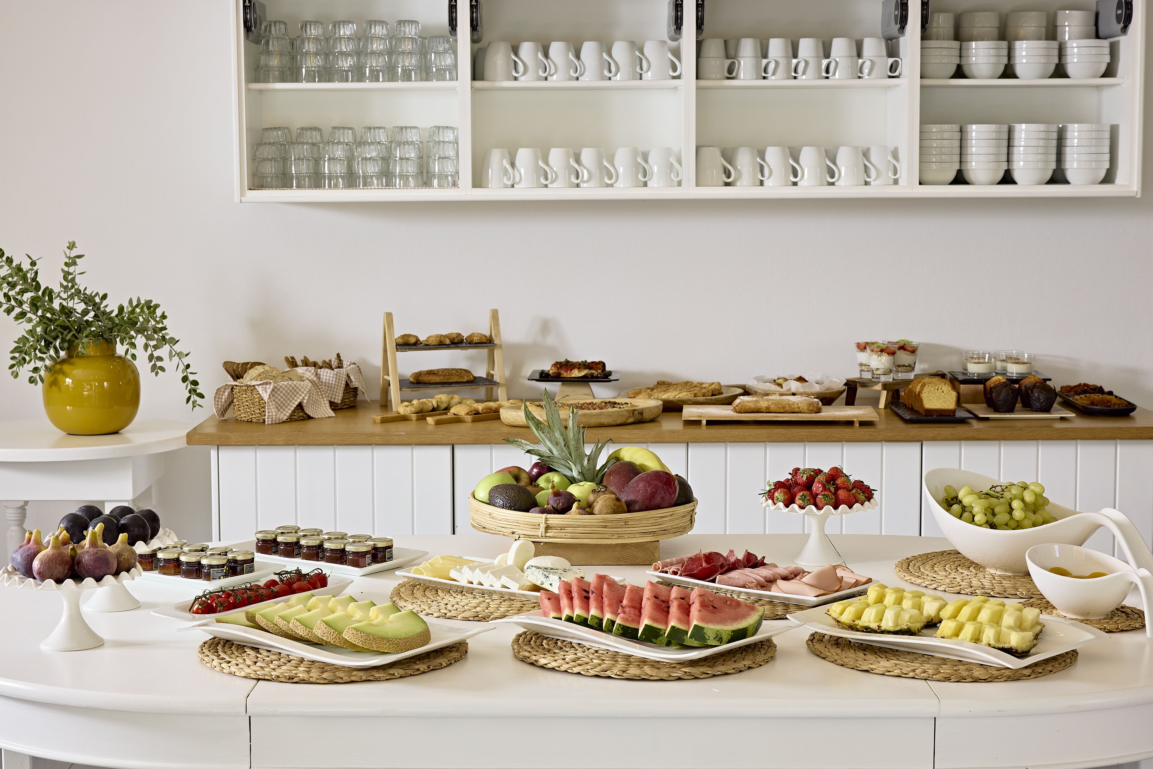 A buffet table with various food items and a fruit basket.