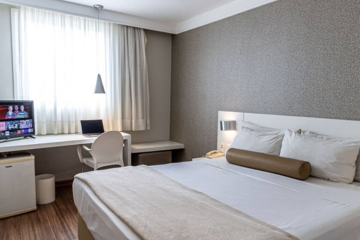 Ein Hotelzimmer mit Bett, Schreibtisch, Stuhl und Fernseher.