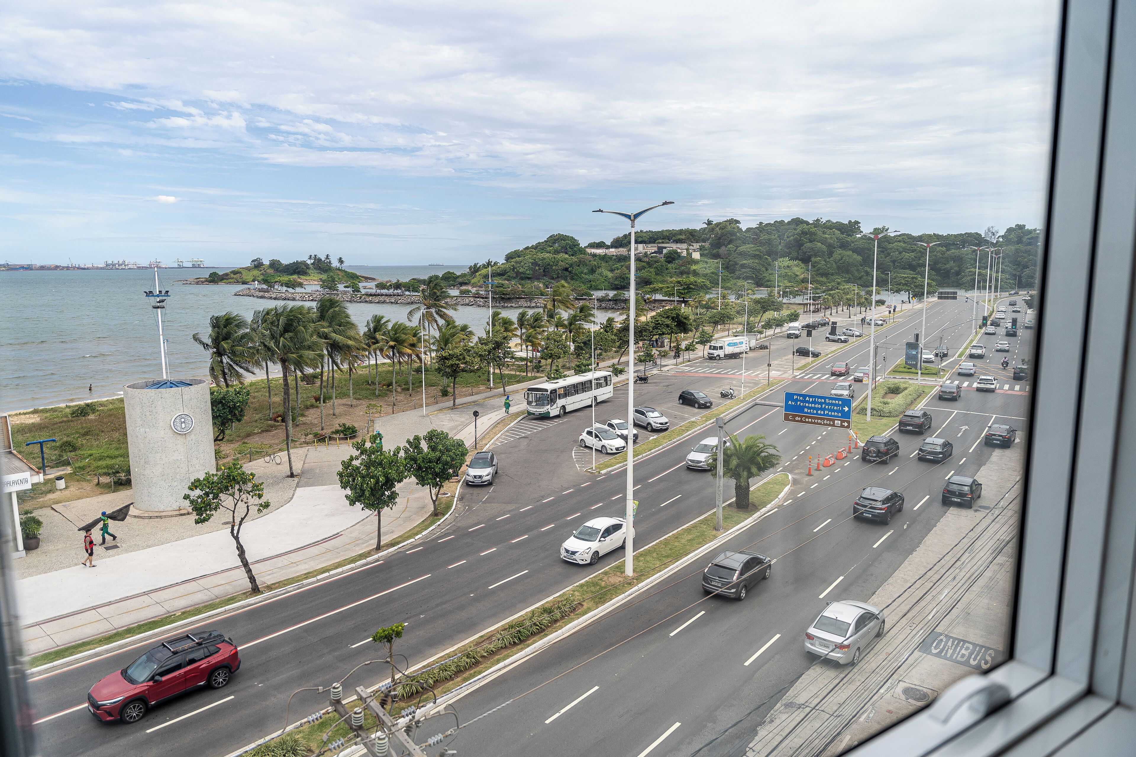 A coastal road with a view of the sea, a pedestrian path, and a bus.