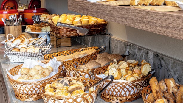 A buffet with various breads, pastries, and a cake on display. - Píer Vitória Hotel (Vitoria)