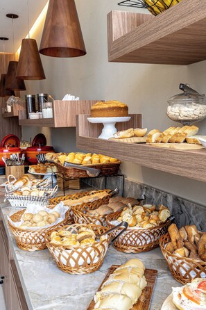A buffet with various breads, pastries, and a cake on display. - Píer Vitória Hotel (Vitoria)