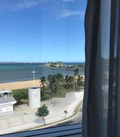 Vista costera con playa, palmeras y cielo despejado.