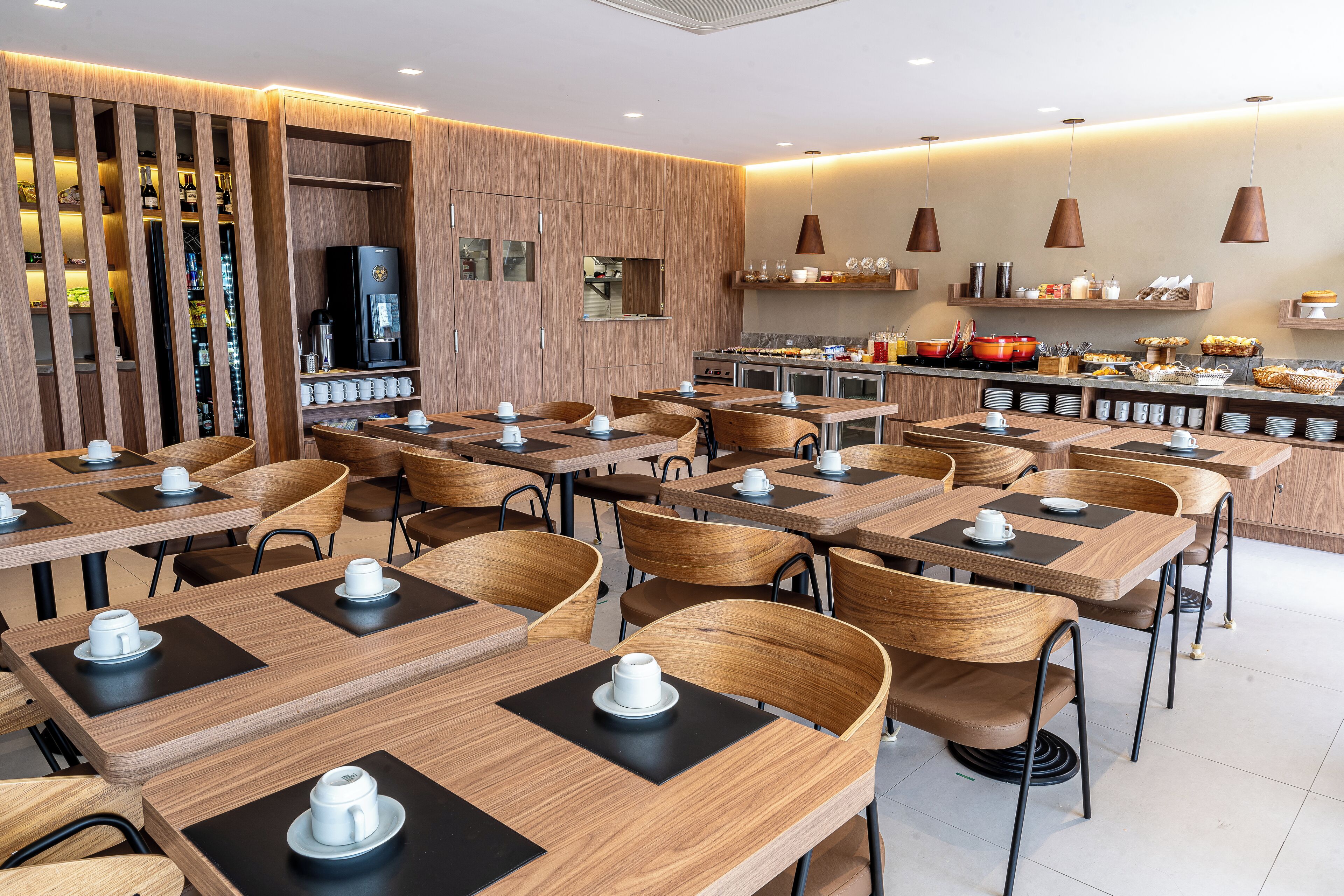 A modern restaurant with wooden tables and chairs, a coffee station, and a buffet area.