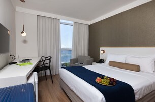 Habitación de hotel con cama, escritorio, silla y vista al mar.