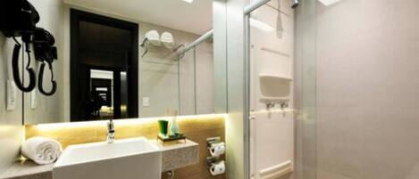 Un baño moderno con cabina de ducha de vidrio, un lavabo blanco con una toalla y un espejo.