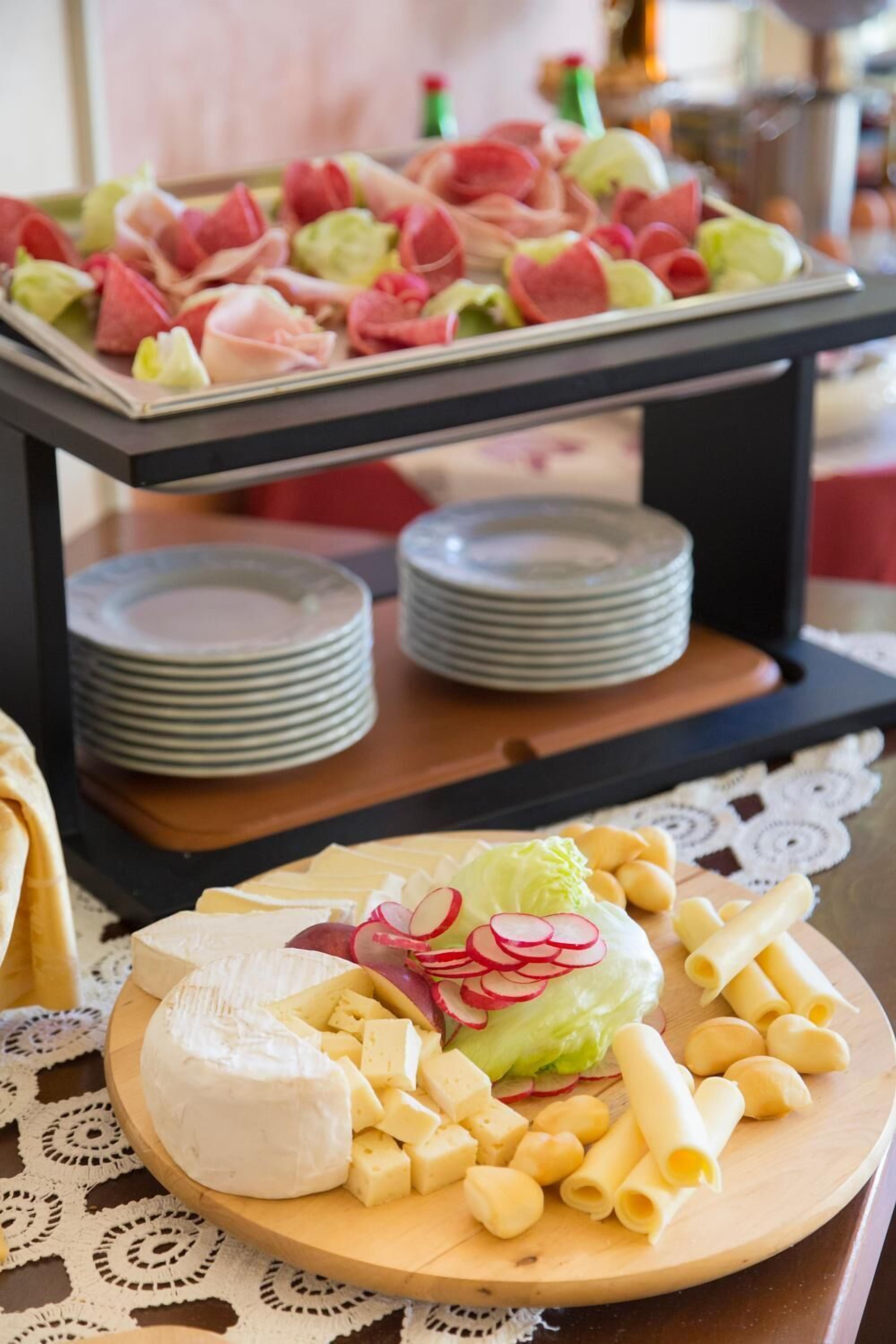 Un tavolo con un tagliere di formaggi, pasta e un vassoio di antipasti.