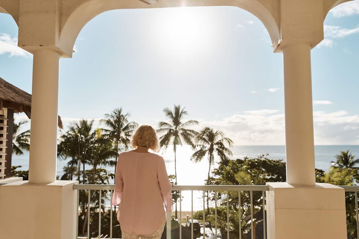 Ein Balkon mit Blick auf den Ozean und Palmen.
