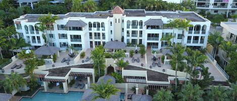 A resort with multiple buildings, outdoor pools, and palm trees.