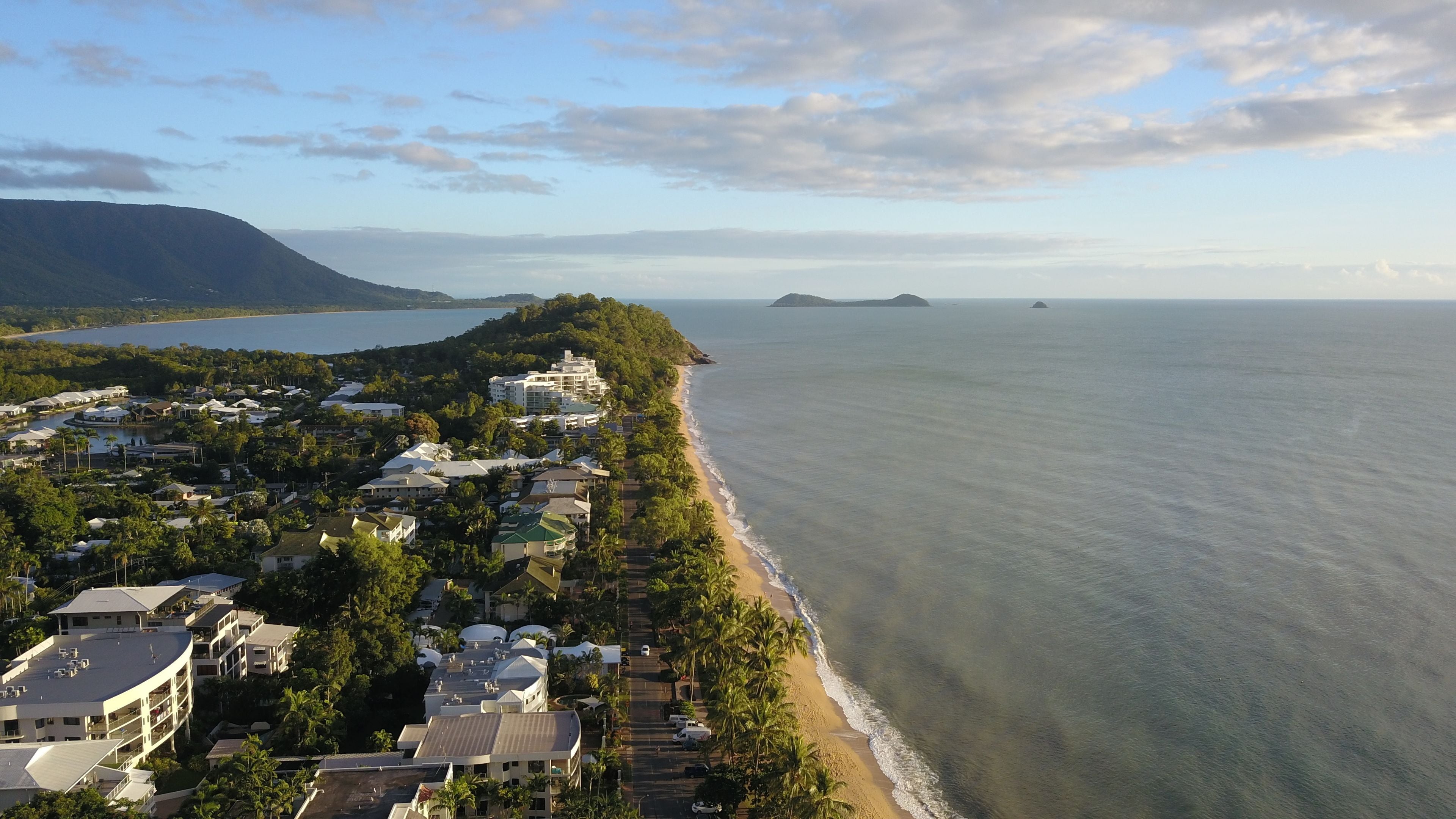 Une ville côtière dotée de propriétés en bord de mer, d’un port de plaisance et bordée de montagnes.