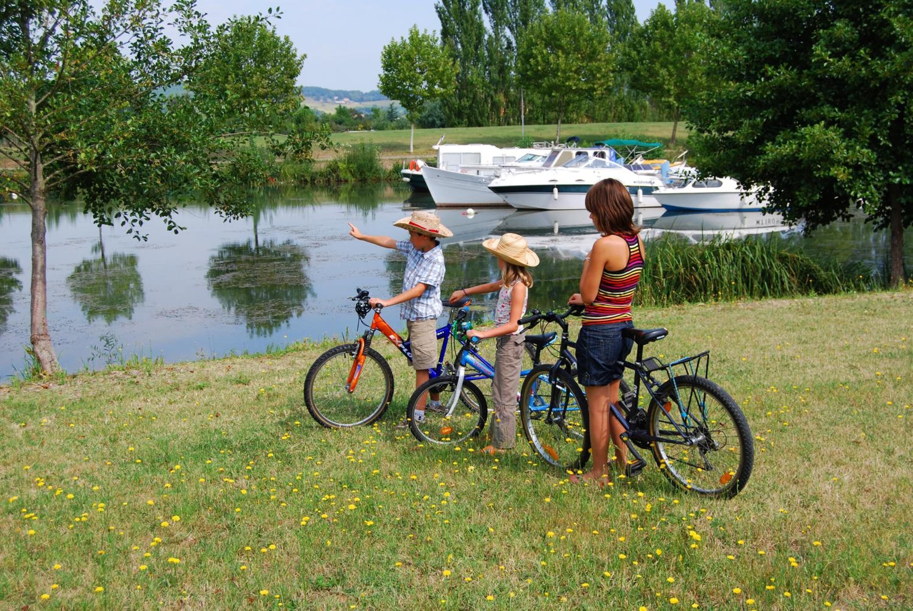 A grassy area with a body of water and boats in the background.