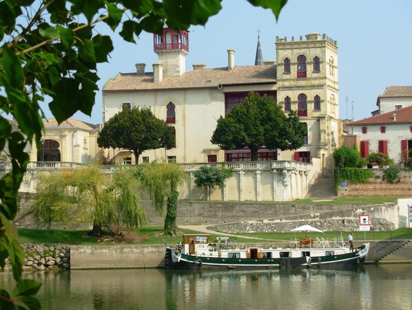 Un edificio histórico con una torre, un río y un bote atracado al frente.