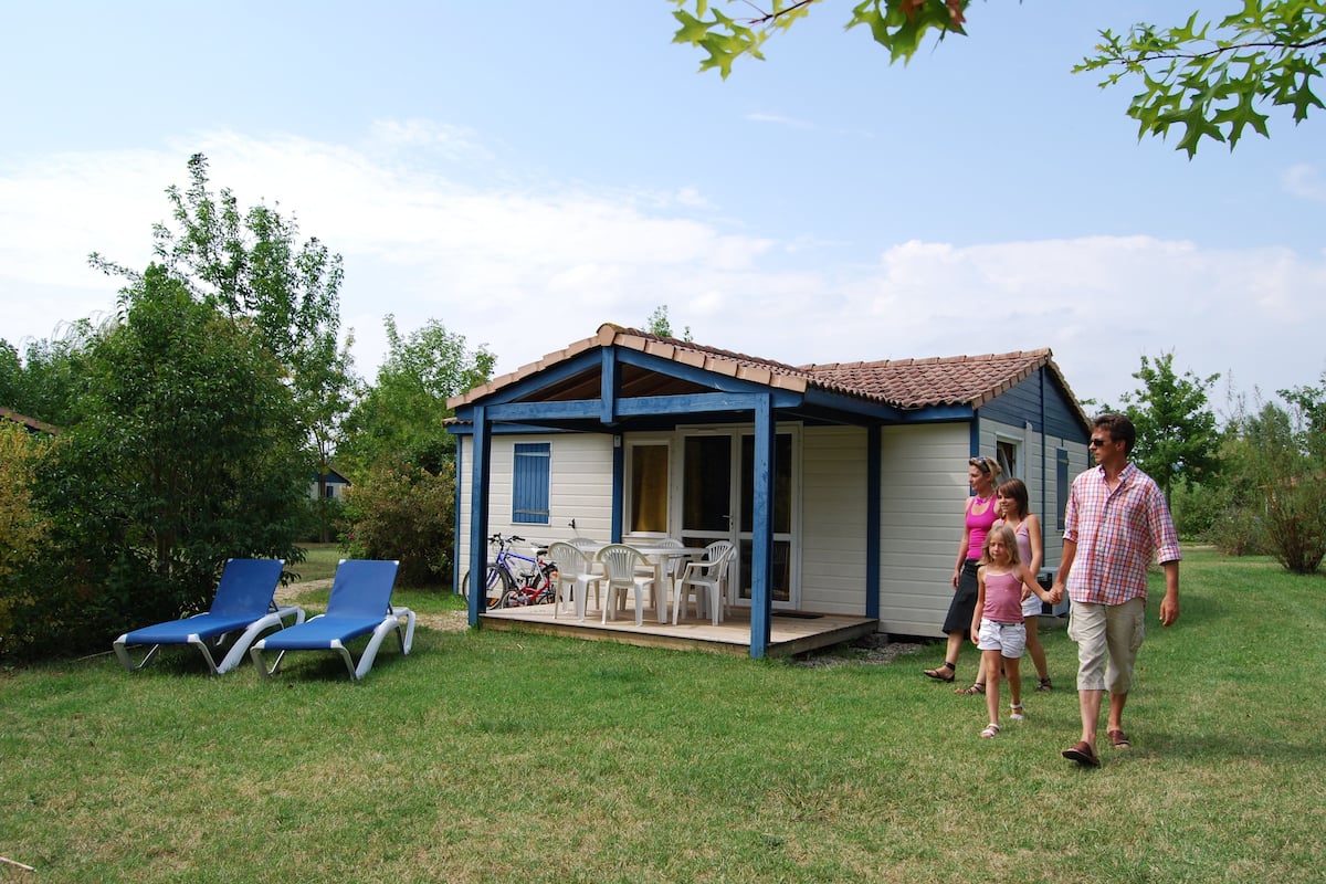 A small, single-story house with a porch and outdoor seating area.