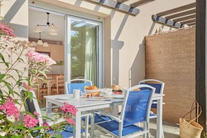 A dining area with a table set for two, chairs, a basket of bread, and a window with a view of the interior. - Résidence Odalys Le Hameau du Lac (Rignac)