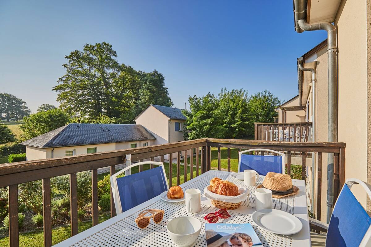 A balcony with a table set for breakfast, including bread, a basket, and a magazine.