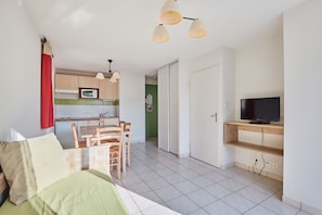 A compact living space with a kitchenette, a dining area, a TV, and a bed. - Résidence Odalys Le Hameau du Lac (Rignac)