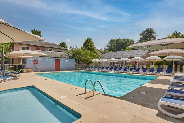 A pool area with lounge chairs and umbrellas. - Résidence Odalys Le Hameau du Lac (Rignac)