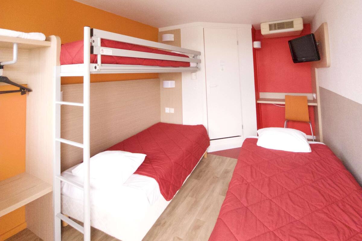 A room with bunk beds, a wardrobe, a television, and a desk.