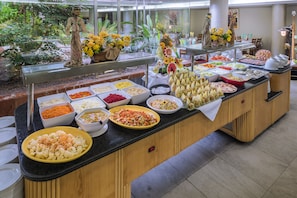 Um buffet com diversos tipos de comida e uma estátua decorativa.