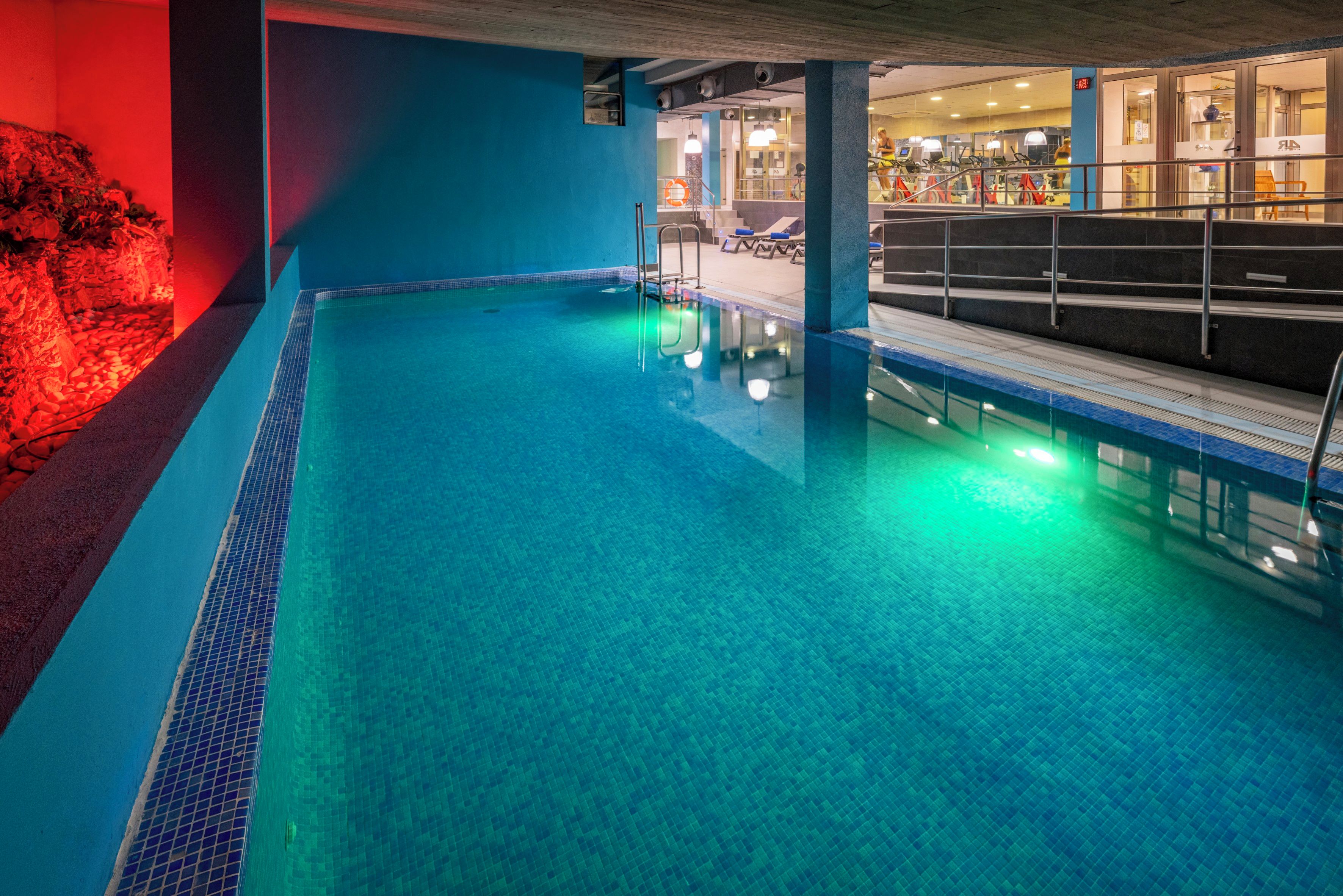 An indoor swimming pool with clear water, surrounded by walls painted in blue and red.