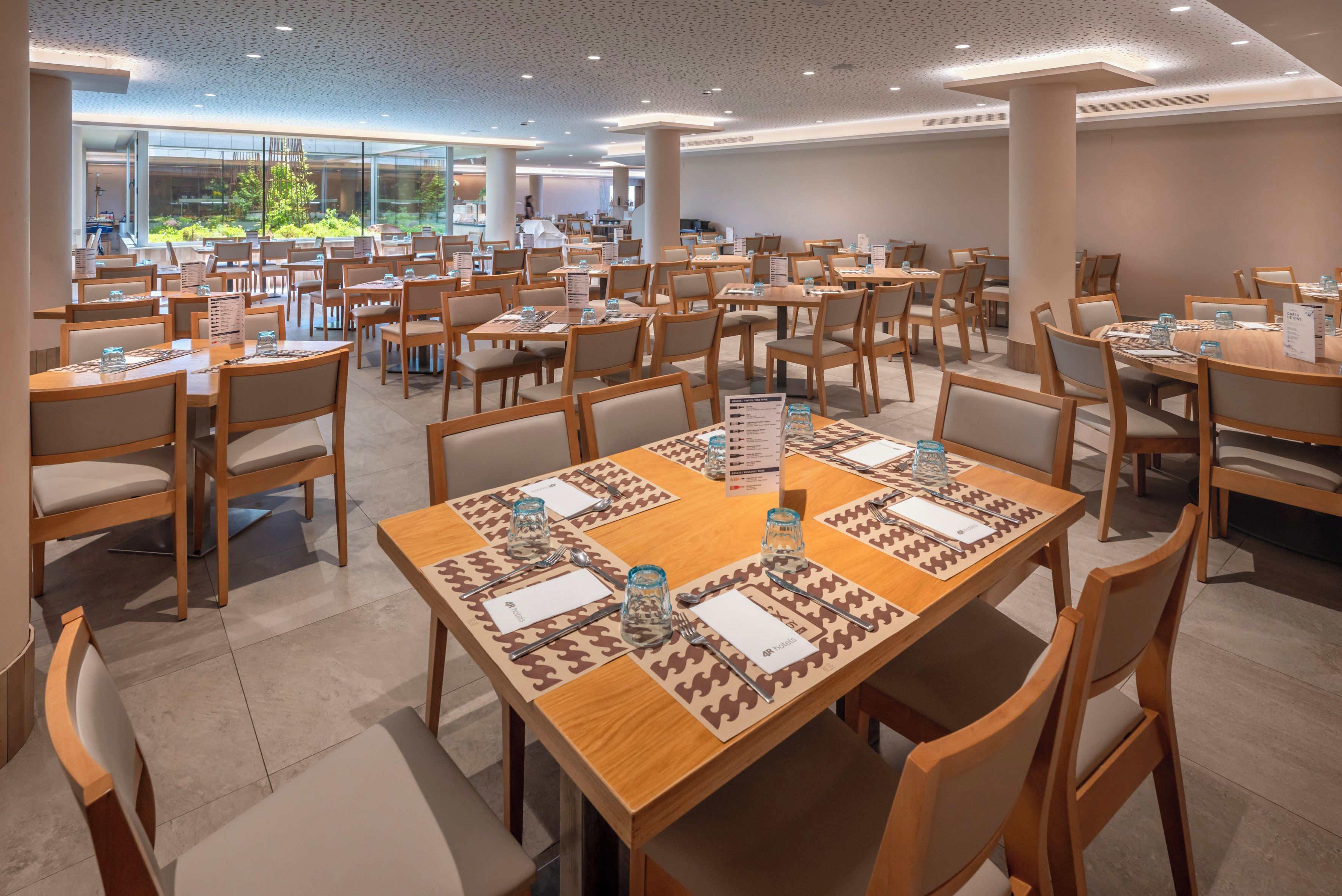 A spacious hotel dining area with multiple tables and chairs, arranged in a grid pattern.