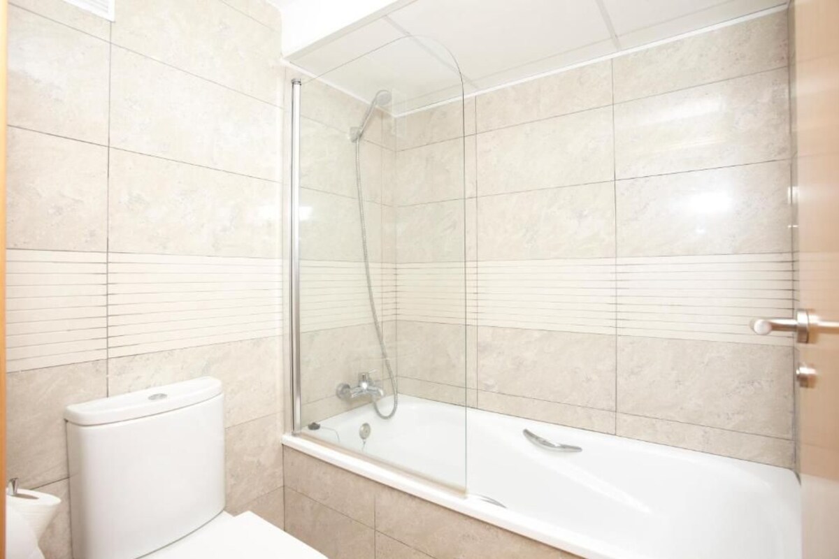 Un baño con ducha de vidrio, inodoro blanco y bañera.
