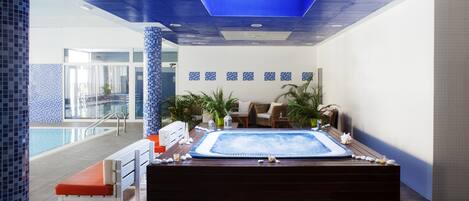Un área de spa con un jacuzzi, asientos y vistas a la piscina.