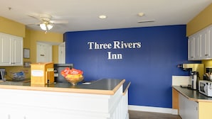 Una zona de cocina con pared azul, un letrero que dice "Three Rivers Inn" y una encimera con una cesta de aperitivos.