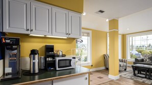 Una cocina funcional con gabinetes blancos, microondas, cafetera y dispensador de agua.