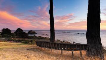A bench overlooking a coastal area with a sunset view.