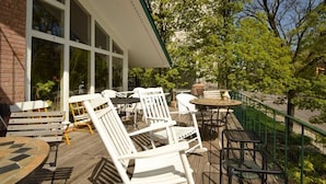 An outdoor deck with white chairs and tables, a brick building, and a green railing. - Ann Arbor B&B Inn (Ann Arbor)