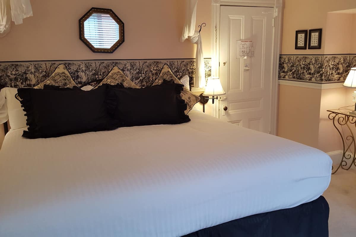 A neatly made bed with a white duvet, black pillows, and a decorative headboard.