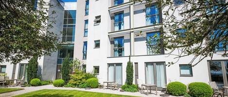 A modern multi-story building with a well-maintained lawn and outdoor seating area.