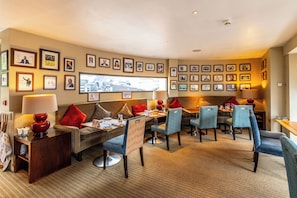 A hotel room with a seating area, a television, and a wall decorated with framed pictures. - Hart's Hotel (Nottingham)