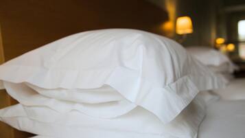Almohadas blancas ordenadas sobre una cama en una habitación de hotel.