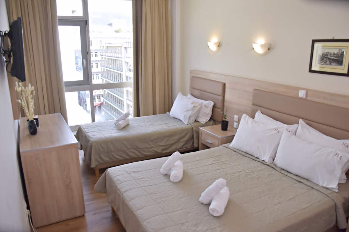 Une chambre d’hôtel avec deux lits, une table de chevet, une commode, une fenêtre avec des rideaux et un luminaire fixé au mur.