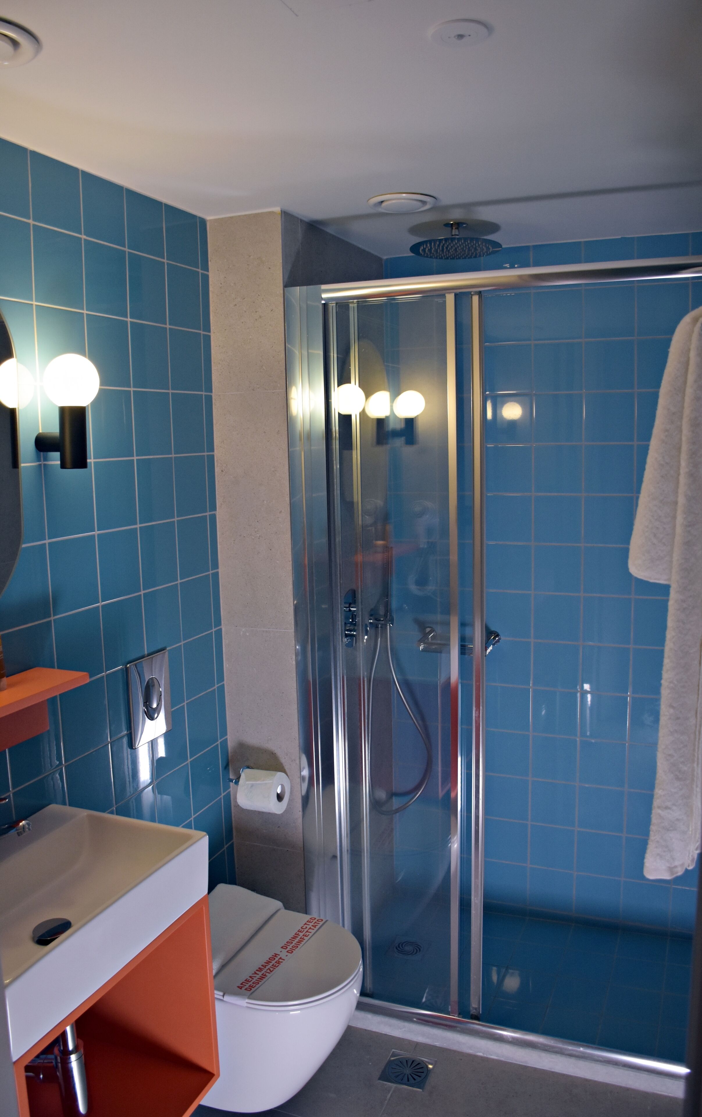 A bathroom with a glass shower enclosure, a toilet, and a sink with a mirror.