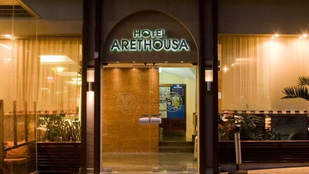 Exterior de l'Hotel Arethousa, amb una entrada ben il·luminada i una zona de recepció visible.