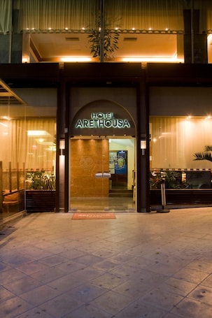 The exterior of Hotel Arethousa with a well-lit entrance and a visible reception area.
