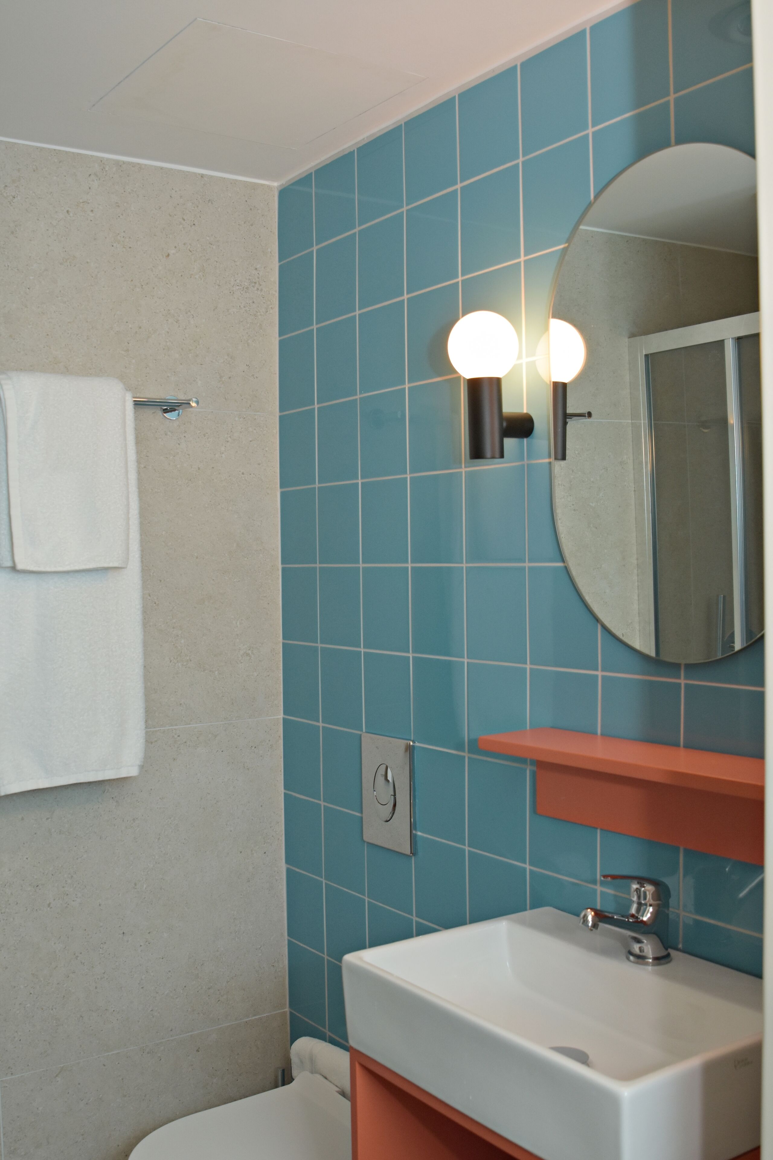 A bathroom with a white sink, a mirror, and a towel hanging on a rack.